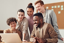 5 colleagues looking at laptop